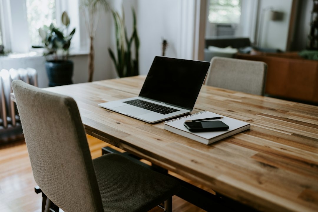Laptop, notebook, and phone on a wooden table.
